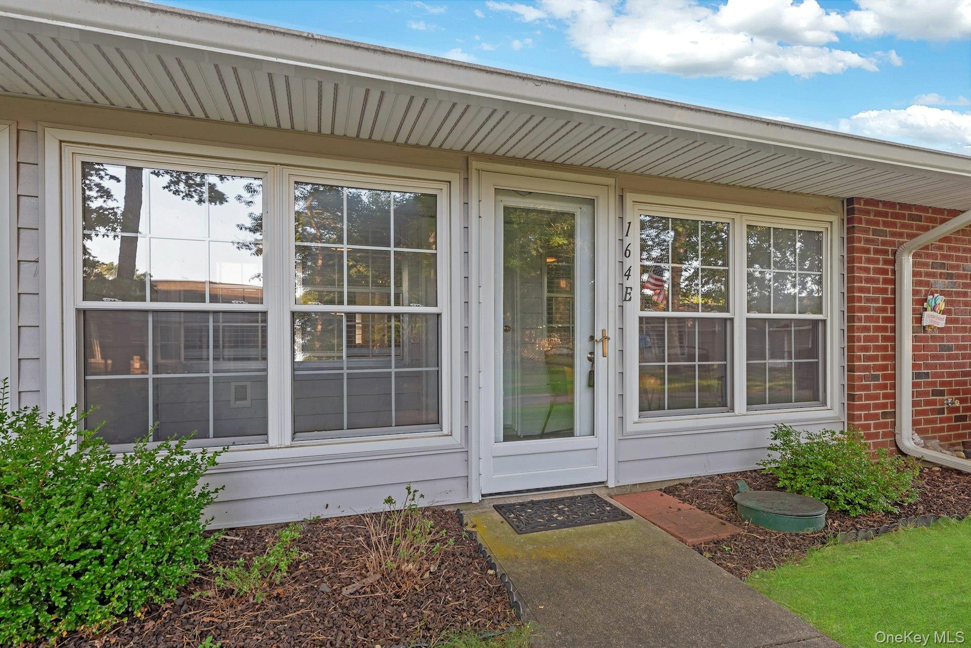 164 Falmouth Court, Unit E Ridge, NY 11961 - Photo 2 of 15 a front view of a house with a garden
