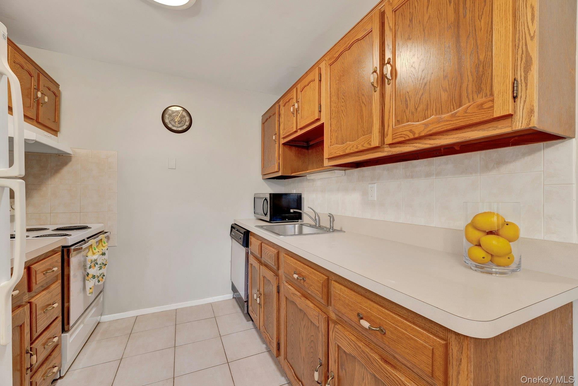 164 Falmouth Court, Unit E Ridge, NY 11961 - Photo 9 of 15 a kitchen with a sink a stove and cabinets