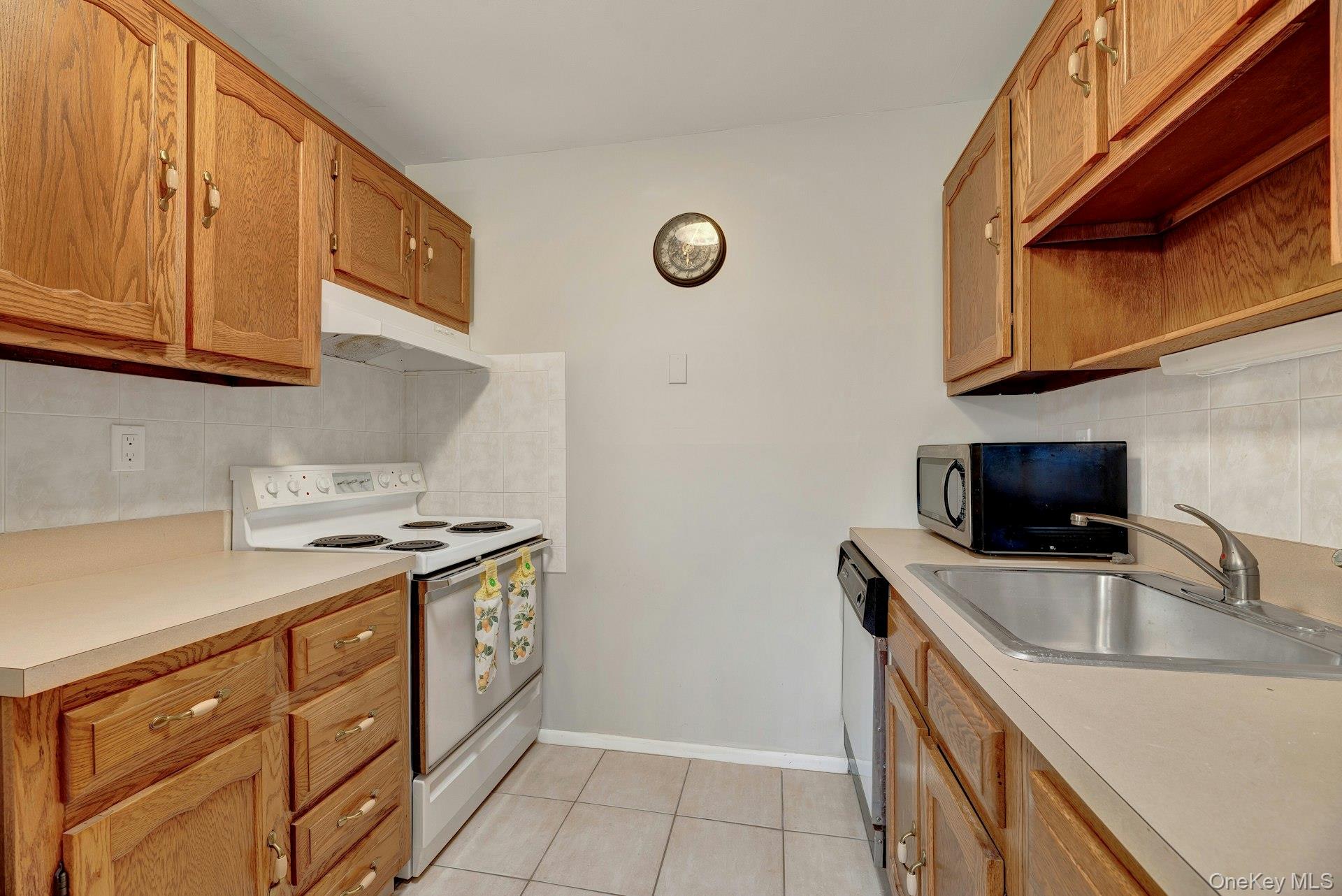 164 Falmouth Court, Unit E Ridge, NY 11961 - Photo 10 of 15 a kitchen with stainless steel appliances granite countertop a sink stove and cabinets
