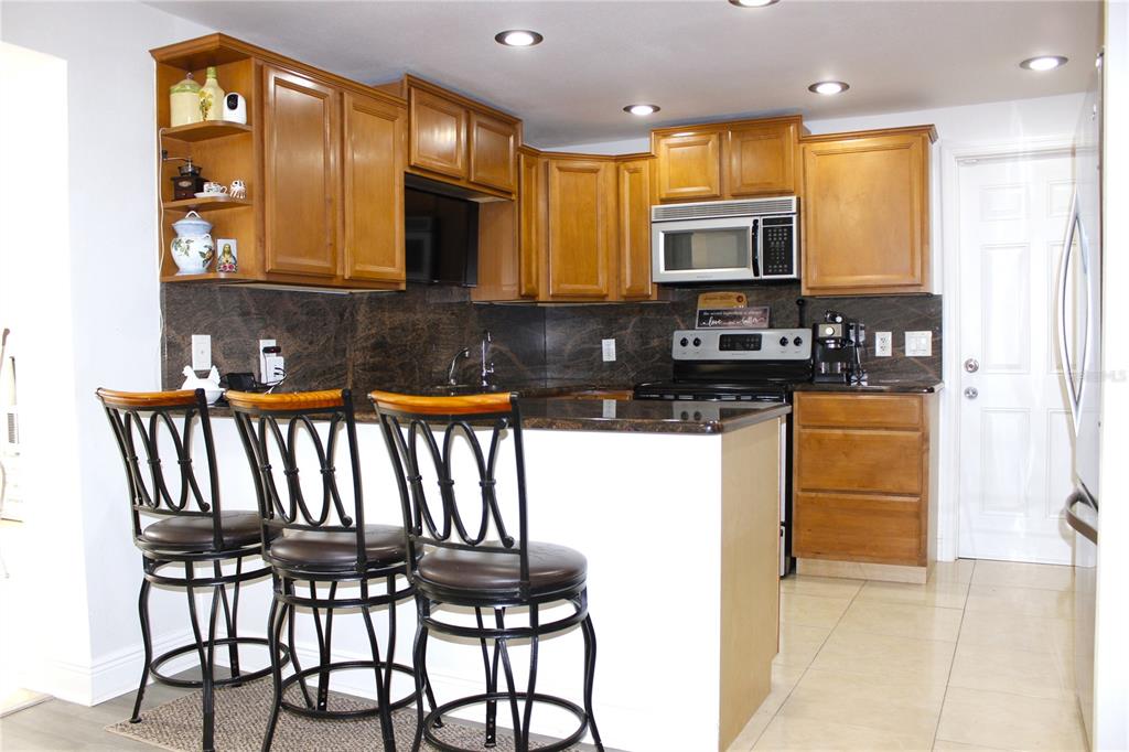 6314 Seabreeze Drive Port Richey, FL 34668 - Photo 12 of 46 a kitchen with granite countertop a stove a sink and a microwave