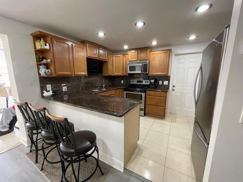6314 Seabreeze Drive Port Richey, FL 34668 - Photo 10 of 46 a kitchen with stainless steel appliances granite countertop a sink a stove a microwave a refrigerator and cabinets
