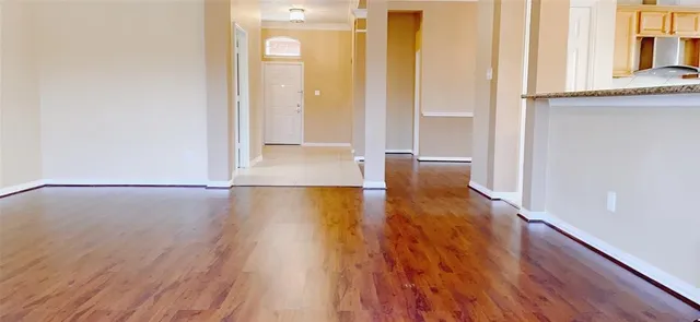 a view of an empty room with wooden floor and a window