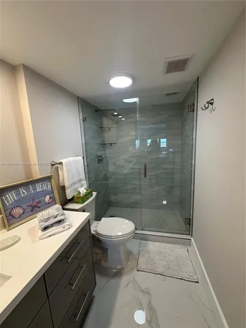a bathroom with a granite countertop sink a toilet and shower