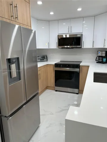 a kitchen with stainless steel appliances wooden cabinets a stove a microwave and a refrigerator