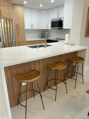 a kitchen with stainless steel appliances granite countertop a table chairs microwave and sink