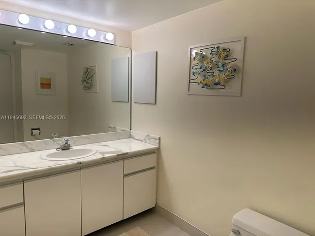 a bathroom with a granite countertop sink a toilet and a mirror