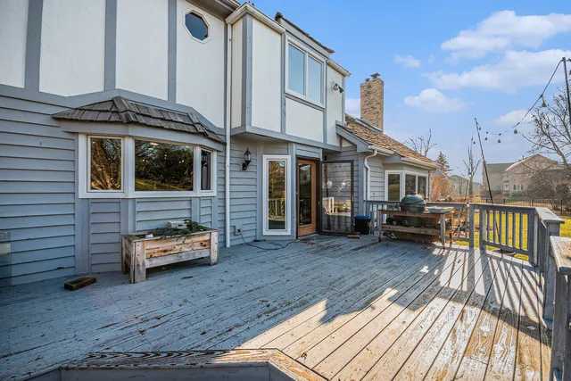 a view of a house with a barbeque and wooden deck