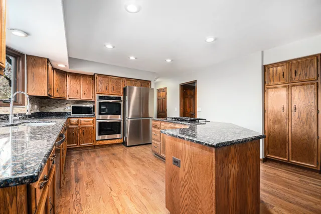 a kitchen with stainless steel appliances granite countertop a stove refrigerator sink and microwave