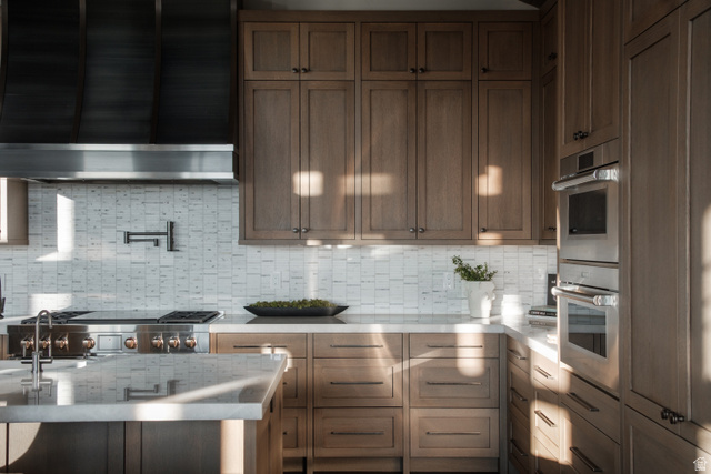 9156 Forest Road, Unit 24 Heber City, UT 84036 - Photo 10 of 42 Gourmet kitchen featuring a professional-grade range, stainless steel appliances, custom wood cabinetry, stone countertops, and a full-height tile backsplash