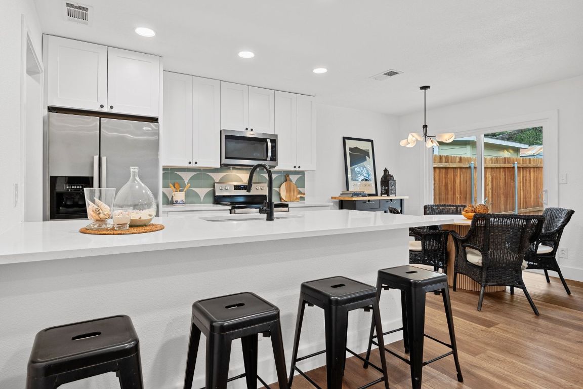 1504 Allen Road, Unit C Austin, TX 78746 - Photo 7 of 26 a kitchen with kitchen island granite countertop a dining table chairs refrigerator and sink