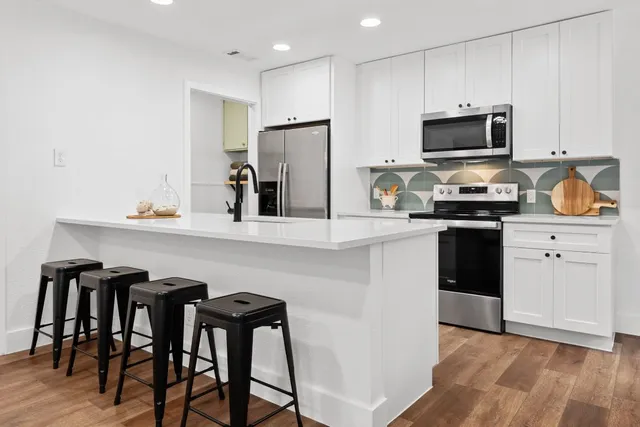 a kitchen with granite countertop white cabinets and stainless steel appliances