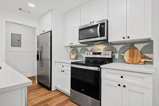 a kitchen with stainless steel appliances white cabinets and a stove a refrigerator with wooden floor