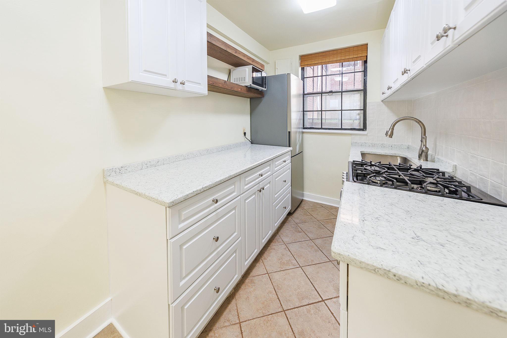 1446 Tuckerman Street Northwest, Unit A6 Washington, DC 20011 - Photo 12 of 25 a kitchen with white cabinets and appliances