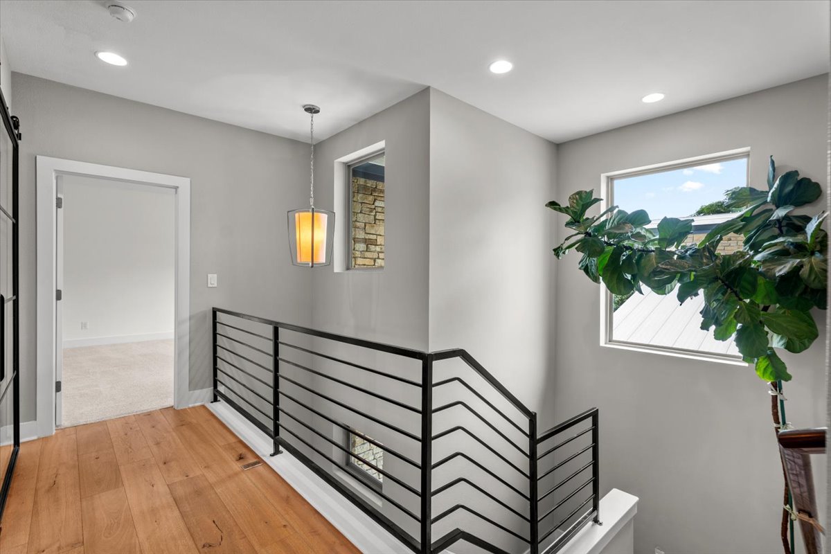 913 Stobaugh Street, Unit B Austin, TX 78757 - Photo 28 of 40 Hardwood flooring extends throughout this naturally illuminated hallway with modern metal railings and a beautiful large fig tree.