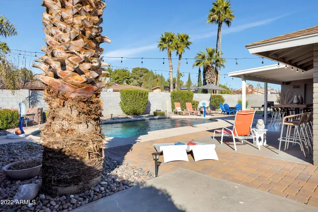 a view of a swimming pool with a table and chairs under an umbrella
