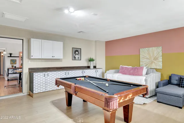 a living room with furniture pool table and kitchen view
