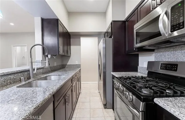 a kitchen with stainless steel appliances granite countertop a sink stove a refrigerator and microwave