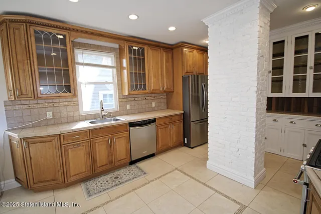 a large kitchen with stainless steel appliances kitchen island granite countertop a refrigerator and a sink