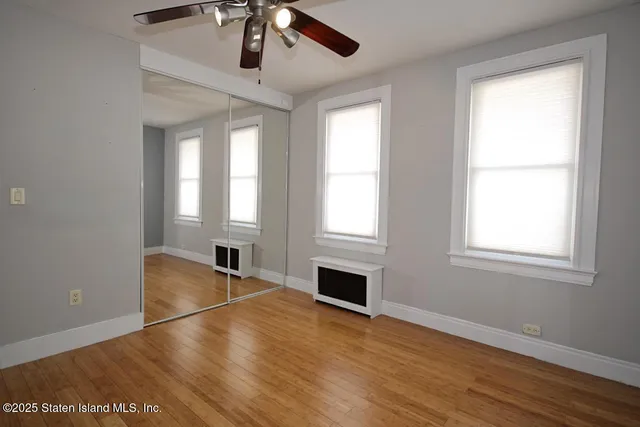 an empty room with wooden floor cabinet and windows