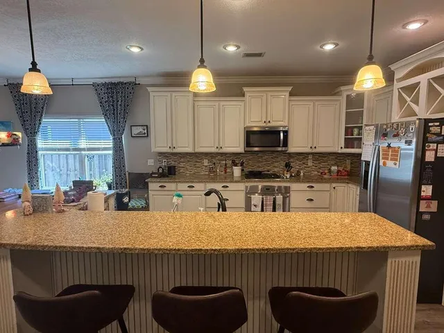 a kitchen with granite countertop a stove a sink a refrigerator a window cabinets and living room view