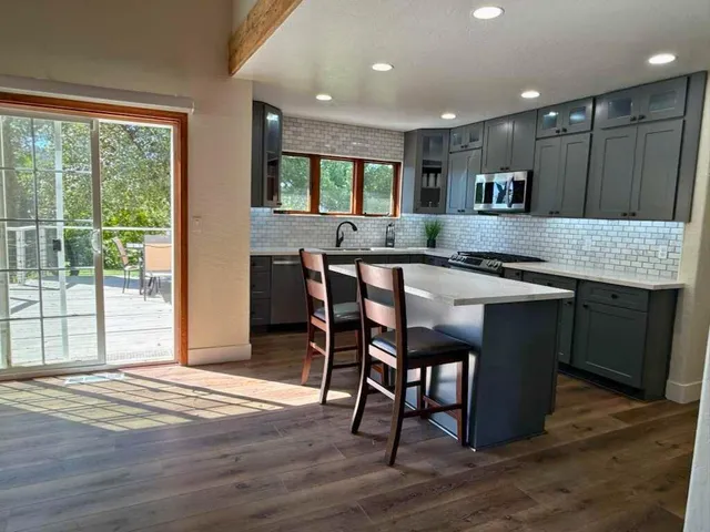 a kitchen with stainless steel appliances granite countertop a kitchen island hardwood floor sink stove dining table and chairs