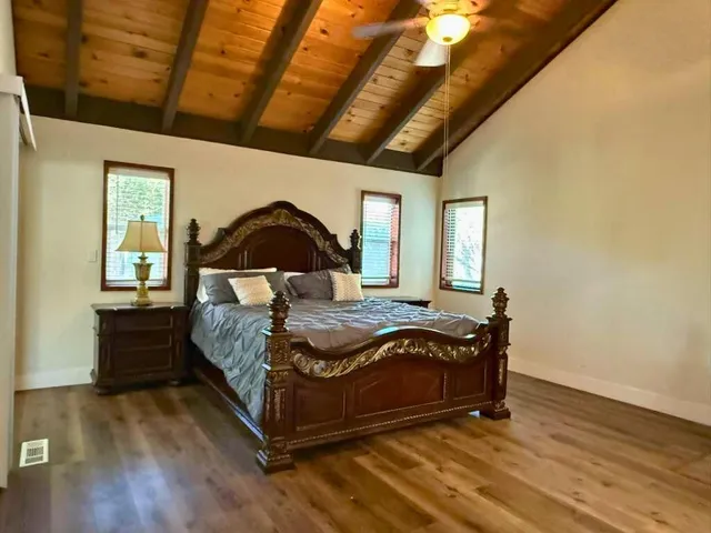 a spacious bedroom with a bed and wooden floor
