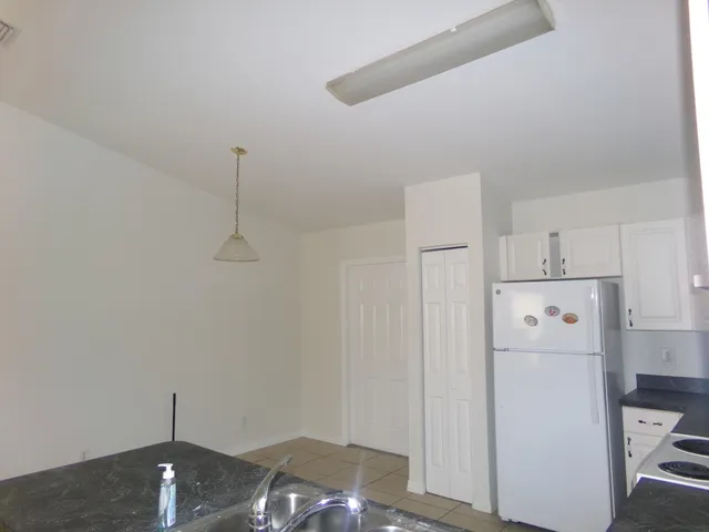 a view of a kitchen with refrigerator and white cabinets