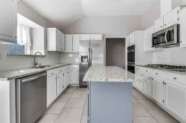a kitchen with granite countertop a sink stainless steel appliances and white cabinets