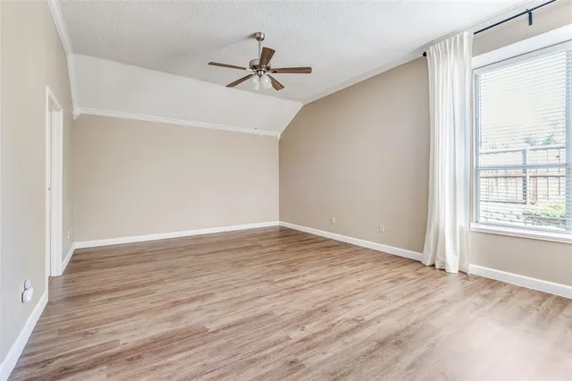 a view of empty room with wooden floor and fan