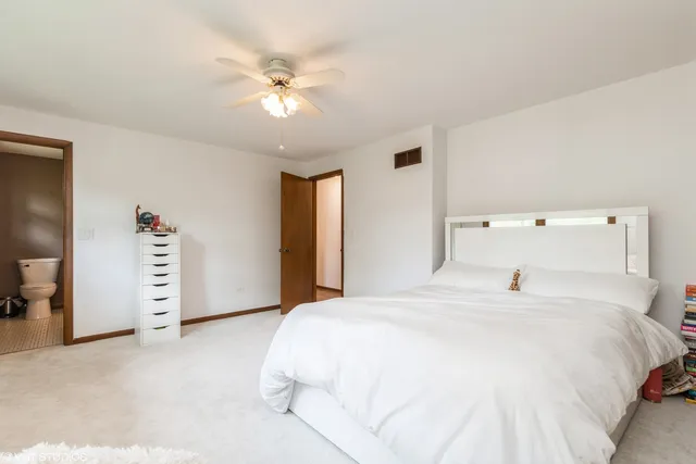 a bedroom with a white bed and ceiling fan
