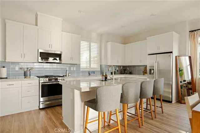 a kitchen with stainless steel appliances granite countertop a stove a sink dishwasher a refrigerator and a dining table with wooden floor