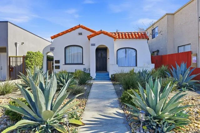 a front view of a house with a big yard and potted plants