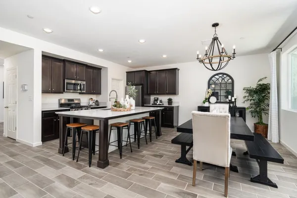 a kitchen with stainless steel appliances granite countertop a stove top oven a sink dishwasher a dining table and chairs with wooden floor