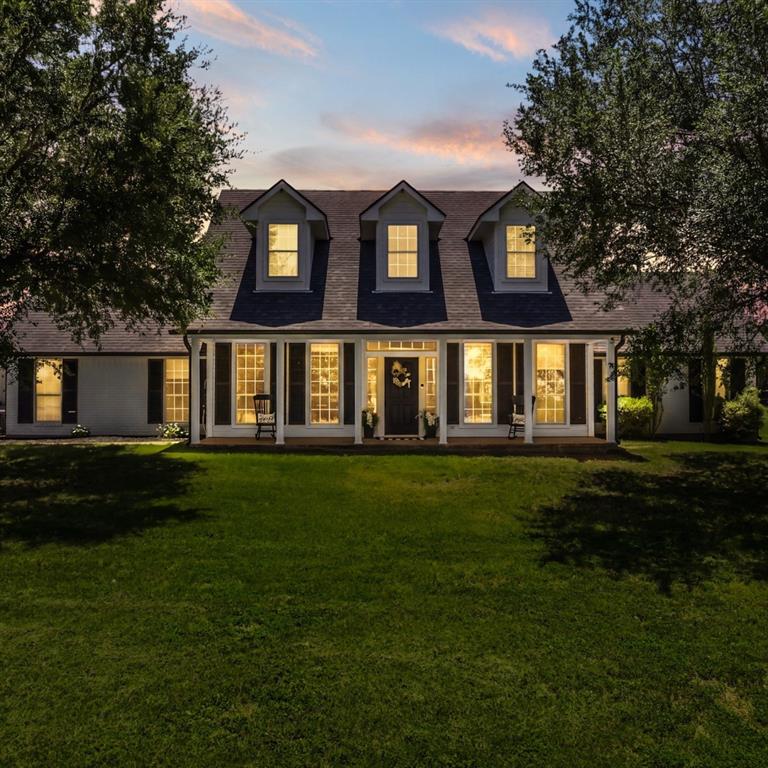 Expansive front lawn with mature trees framing the property