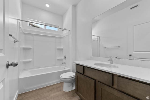 1338 West 2350 South, Unit 19 Perry, UT 84302 - Photo 7 of 14 Bathroom featuring a white integrated tub and shower unit, wood-finish flooring, a contemporary vanity with a white countertop and undermount sink, a large wall-mounted mirror, and recessed lighting
