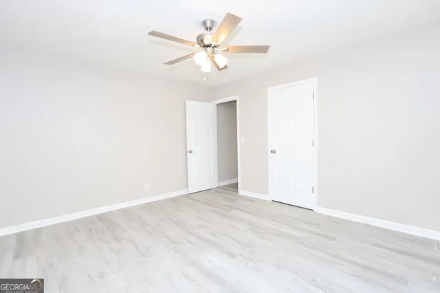 an empty room with wooden floor and ceiling fan