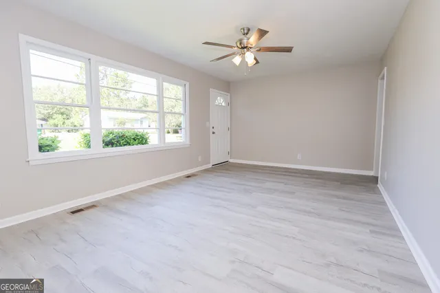 an empty room with wooden floor and windows