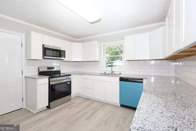 a kitchen with granite countertop a sink wooden floor and stainless steel appliances