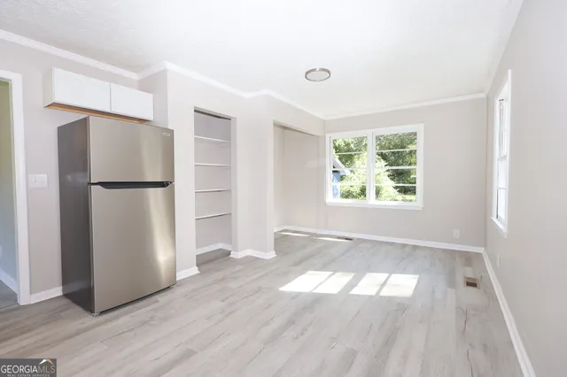 a view of an empty room with a window and wooden floor