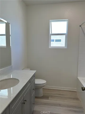 a bathroom with a granite countertop toilet a sink and a window