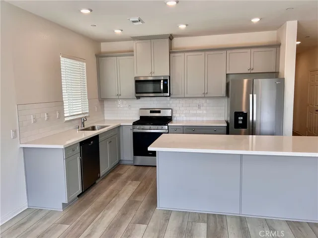 a kitchen with kitchen island granite countertop a sink a counter top space stainless steel appliances and cabinets