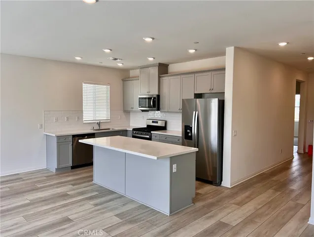 a large kitchen with stainless steel appliances granite countertop a large counter top a stove a refrigerator and a sink