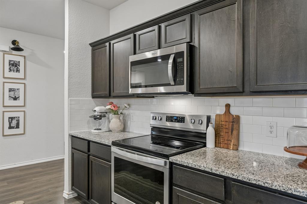 1107 Ringgold Road Forney, TX 75126 - Photo 12 of 27 Kitchen featuring dark wood-finish cabinetry, granite countertops, stainless steel appliances, and a white subway tile backsplash