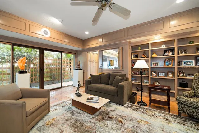 a living room with furniture a rug potted plant and a large window