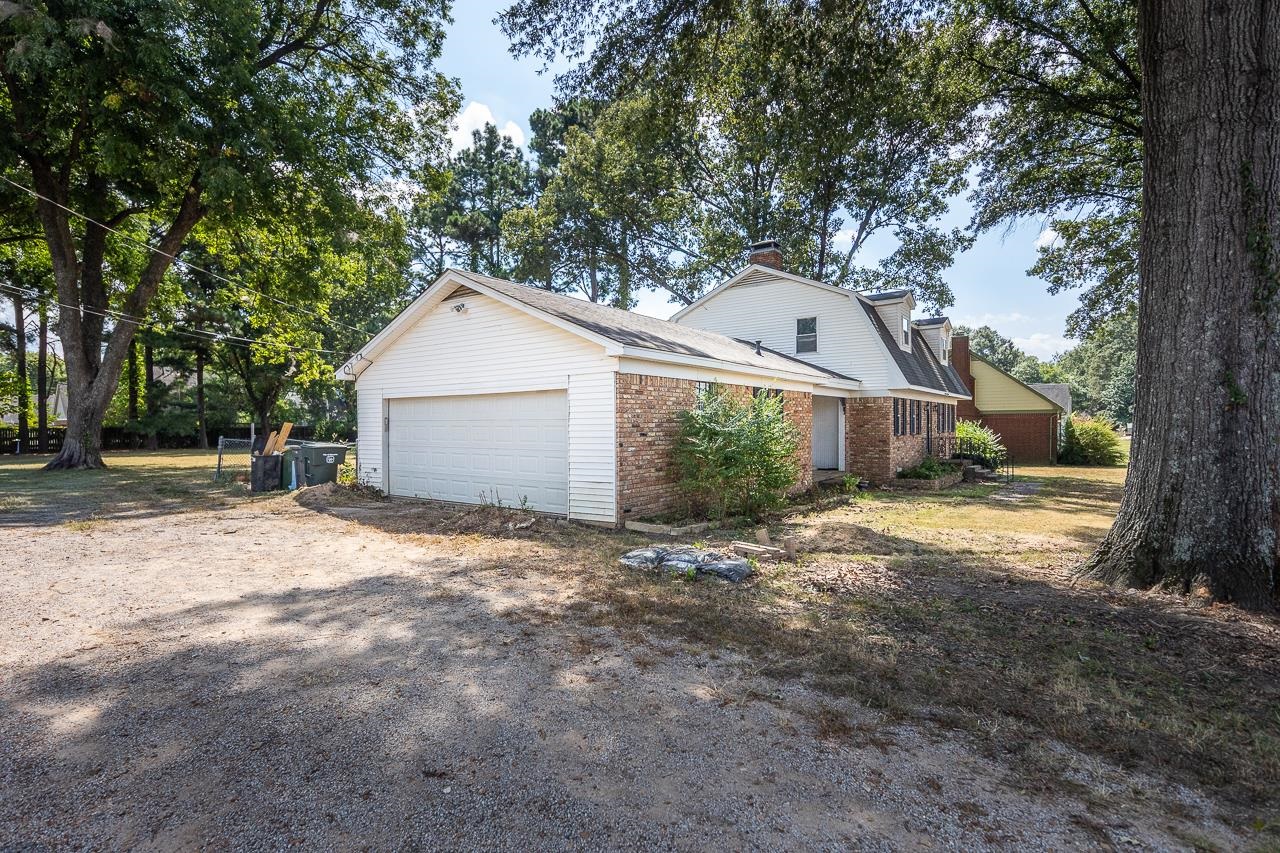 2718 Kate Bond Road Memphis, TN 38133 - Photo 36 of 39 View of side of home with brick siding, a gambrel roof, a chimney, driveway, and a garage