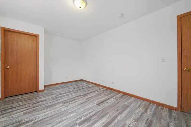 a view of an empty room with wooden floor and closet