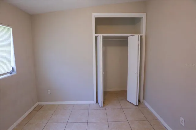 a view of an empty room with closet and a window