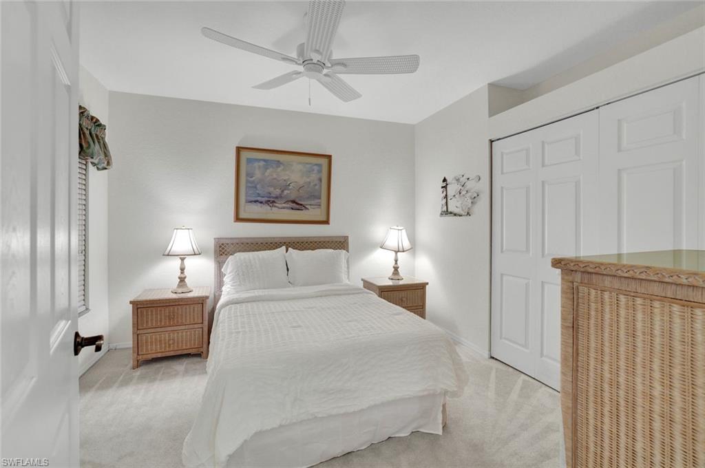 6883 Redbay Park Road, Unit 102 Naples, FL 34109 - Photo 13 of 22 a bedroom with a bed and a night stand