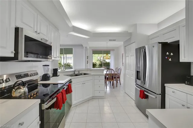 a kitchen that has a lot of cabinets a sink and appliances