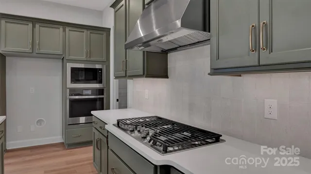 a large kitchen with a large counter top a sink stainless steel appliances and cabinets